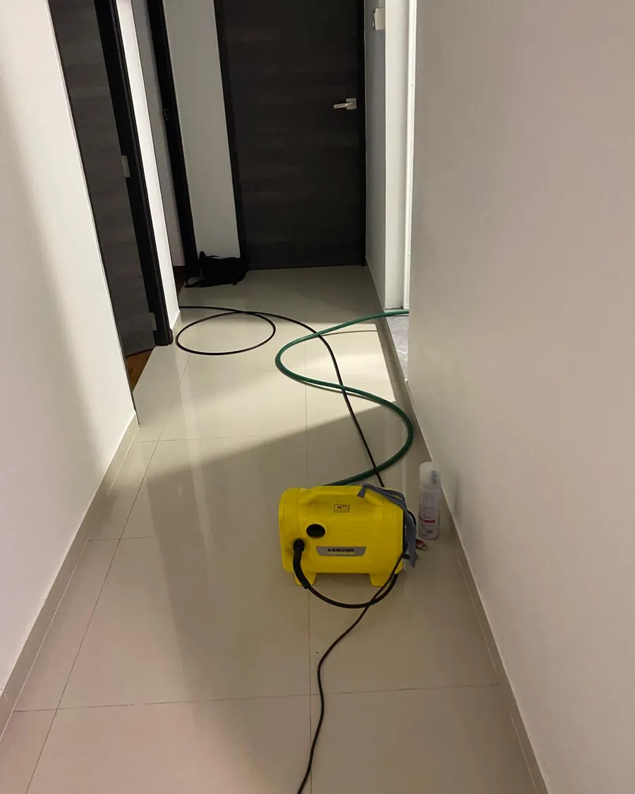 Portable pressure washer and hose set up in the corridor of a Singapore flat for an aircon chemical overhaul
