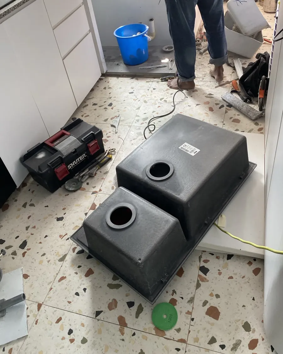 New double-bowl kitchen sink on the floor beside a toolbox during an installation in Singapore