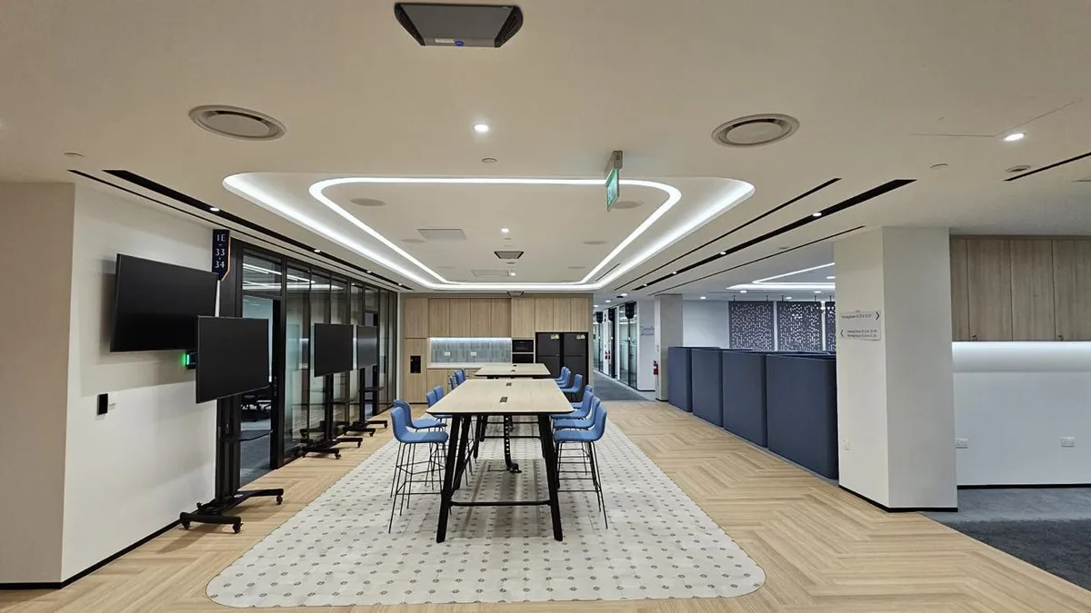Open-plan office in Singapore with a false ceiling, downlights and a cove-lit feature panel